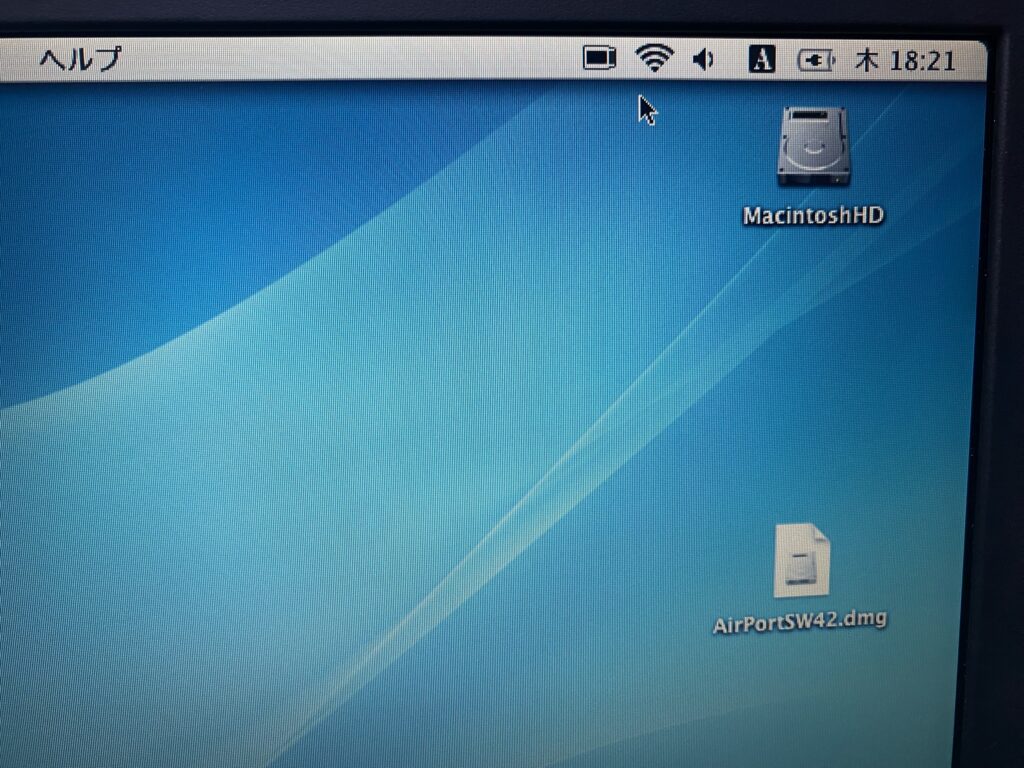 Mac OS X Panther のデスクトップ。メニューバーの AirMac アイコンが黒く塗りつぶされて接続済みを示し、デスクトップに AirPortSW42.dmg が置かれている
