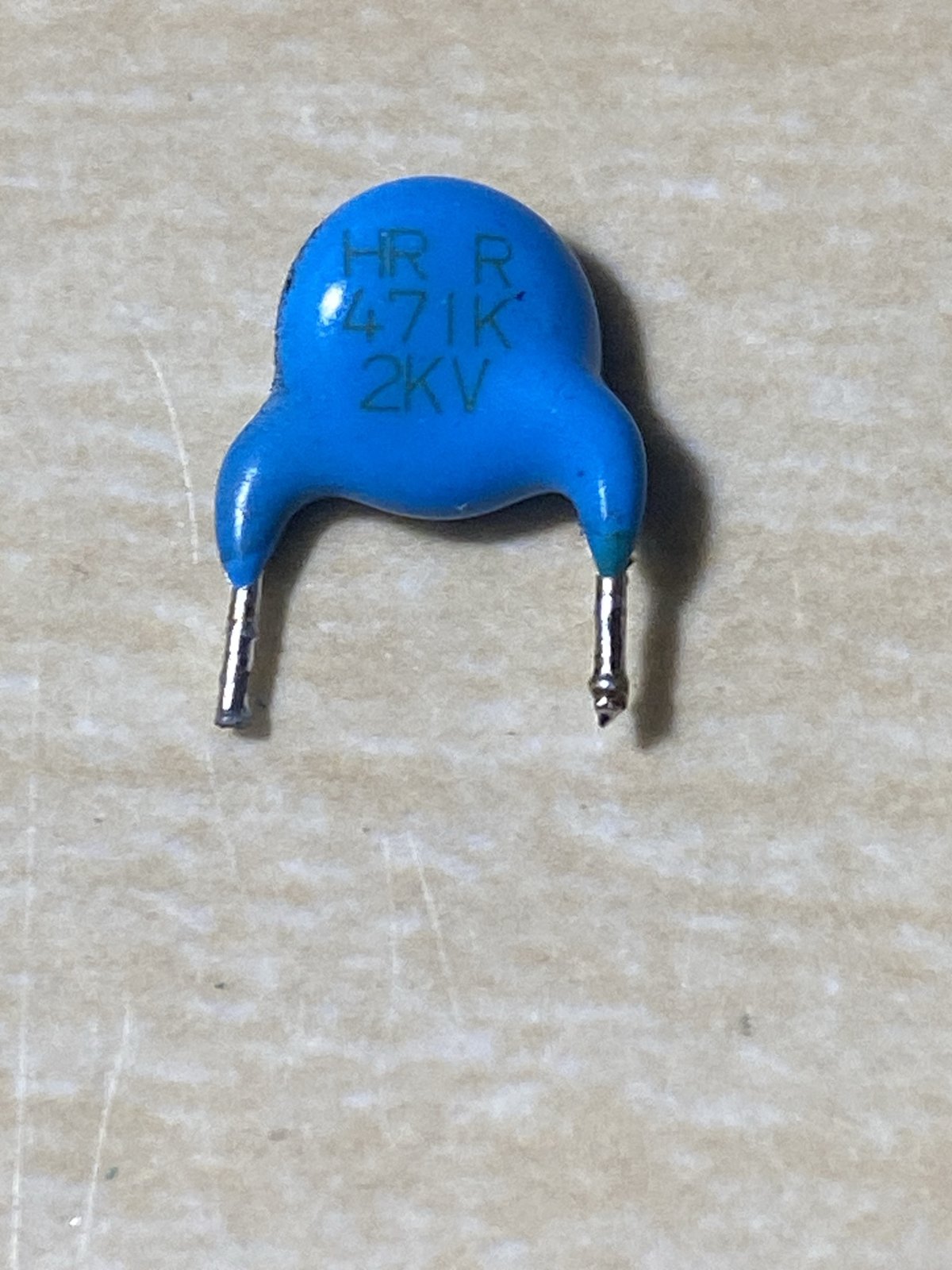 青いセラミックコンデンサ。表面に「HR R 471K 2KV」と印字されている